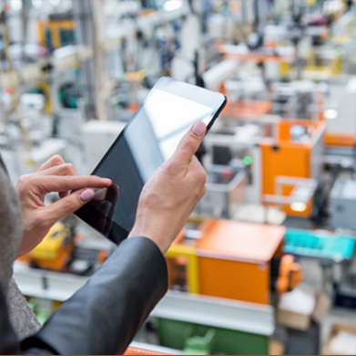 A professional reviewing benefits on a tablet above a large facility floor